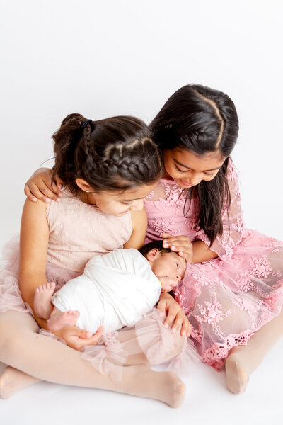 Studio Portrait session of newborn baby with his two sisters