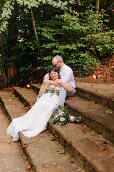 A couple sits holding one another on stairs outdoors