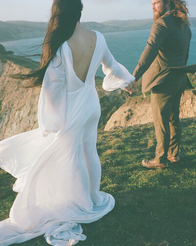 Couple in wedding attire holding hands and looking over San Francisco bay