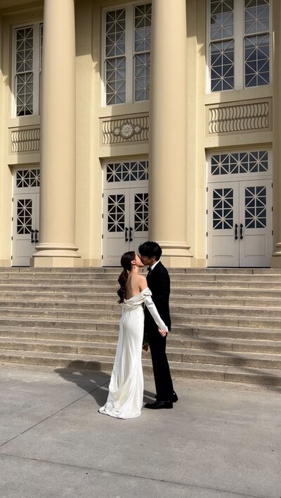 bride and groom kiss in front of wedding venue steps