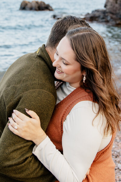 Engagement session at Palisade Head in Silver Bay, MN, showcasing the dramatic cliffs and stunning view of Lake Superior, with the couple in the distance, captured by a wedding photographer in MN.