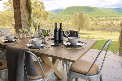 Outdoor dining table at Casa Barragán set for six, overlooking vineyards and rolling green hills in San Miguel de Allende