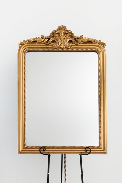 Gold rectangular mirror with ornate frame on black easel stand