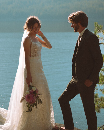 Wedding couple standing next to lake.