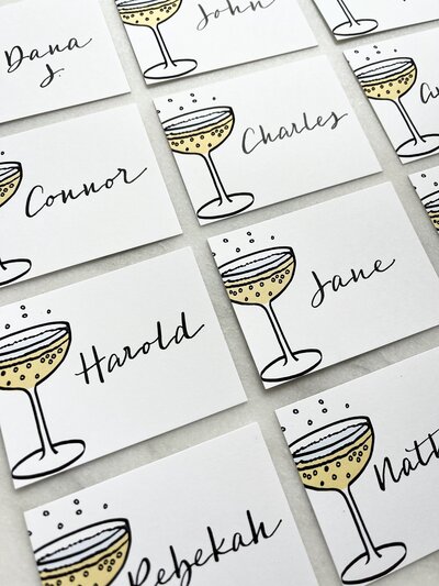 Place cards with champagne glass illustration and black calligraphy