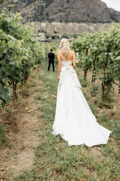 A photo of a bride walking up behind her groom for their first look.