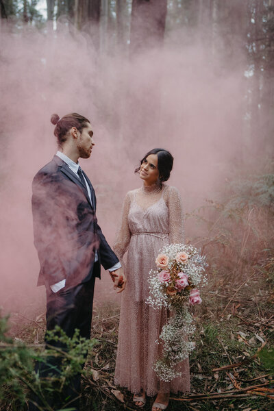 bride and groom in vibrant pink coloured smoke
