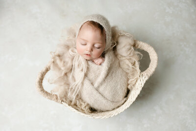 newborn girl in wooden heart bowl holding a mini red felted heart
