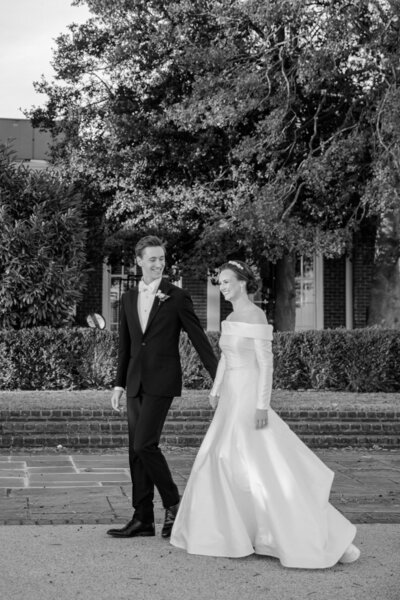 Georgia Wedding Photographer | Black and White Photo of Couple in Classic 50's Style Wedding Attire Walking to Cocktail Hour