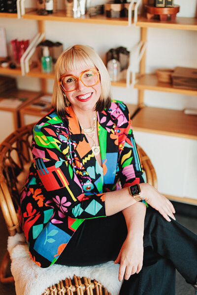 Heather a hair stylist in Eugene sits in a chair a smiles at the camera.
