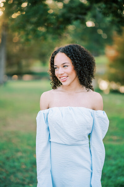 Close up portrait of a woman in a blue dress smiling off to the side
