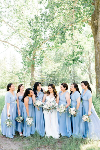 Bride surrounded by smiling bridesmaids in blue dresses