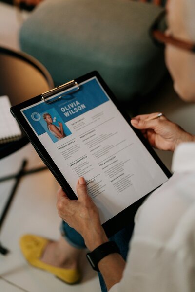 A career coach holds a résumé on a clipboard