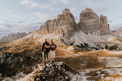 A couple stands on a rock facing each other in Tre Cime national park during their elopement day