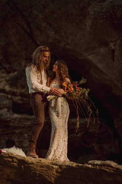 A bride and groom poses on a rock under a natural arch for their elopement in the Blue Ridge Mountains of Tennessee.