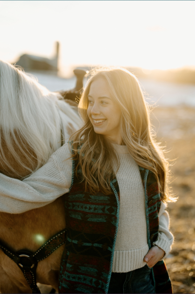 a girl at sunset with her horse