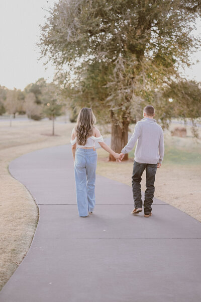 Engaged couple holding hands while walking down a street in fall