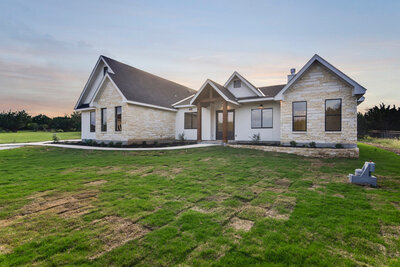 limestone house with black windows and wood columns at front porch