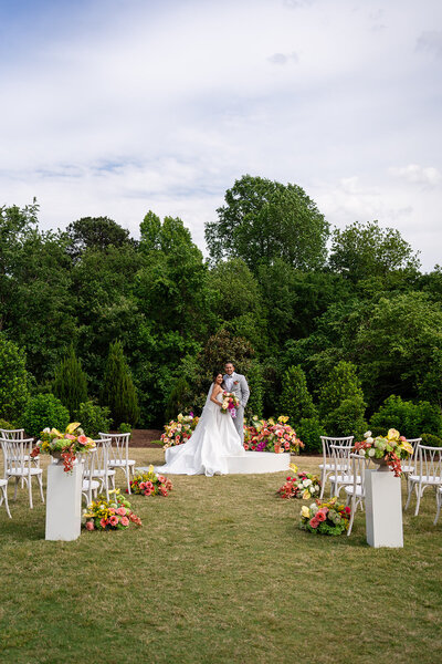 Bride and groom on a circular ceremony pedestal surrounded by colorful florals  