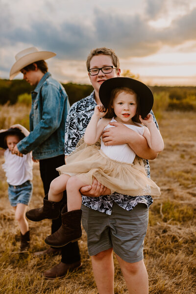 Big brothers playing with their baby sisters during family photos