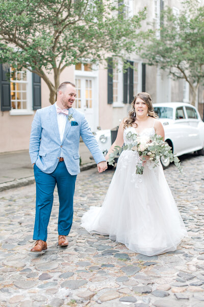 Bride and groom walk down street in downtown Historic Charelston District.