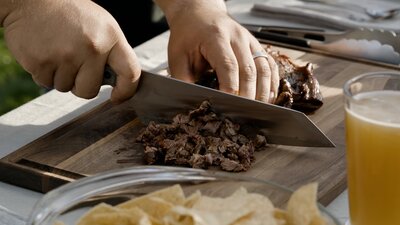 hands using knife to cut meat