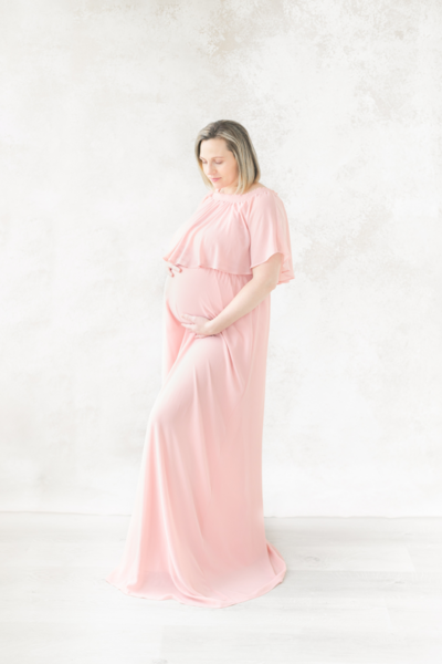 pregnant woman holds baby bump and smiles during boston maternity photoshoot