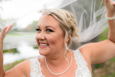 Plus size bride smiles under veil.