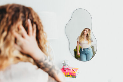 curly haired woman looking in mirror at herself