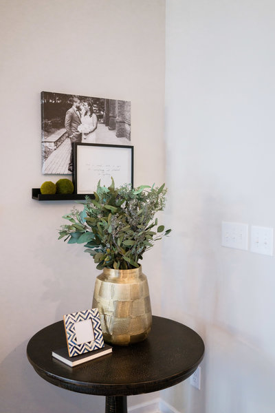 a small table with a plat in a gold vase and a picture frame