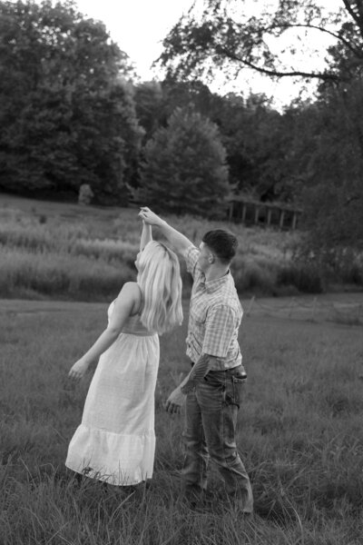 Candid moment of a couple spinning together in an open field during their Kentucky engagement session, full of joy and golden light.