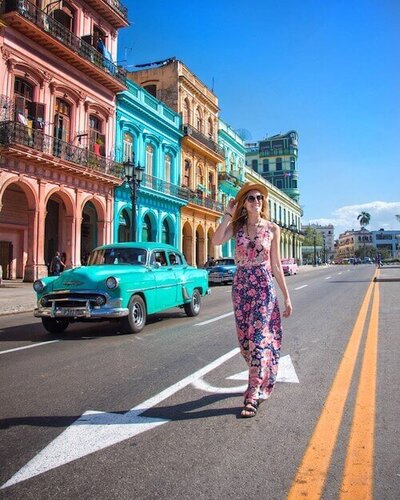 Female designer walks on the street in front of colorful buildings in Havana, Cuba
