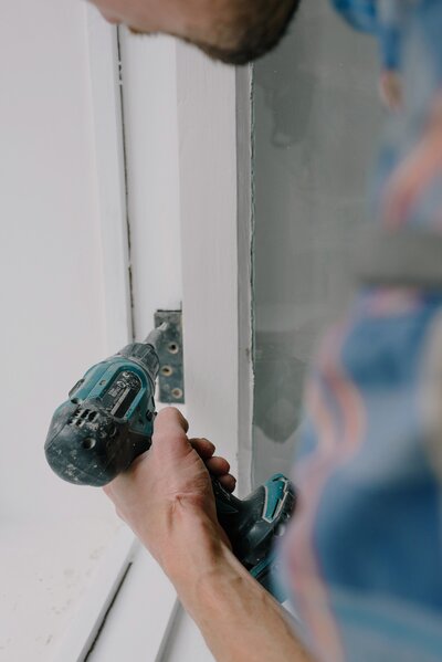 A  man holds a drill while installing a new energy efficient and secure door at United Contractors of Texas