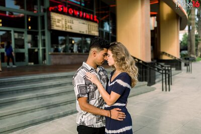 Tender moment during engagement session between engaged couple outside the movie theater in Downtown Brea