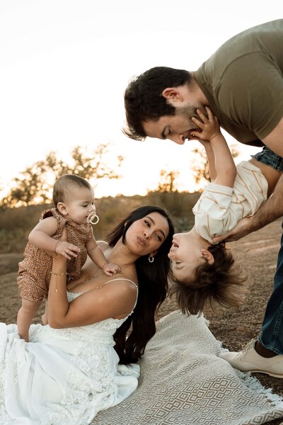 mom holding baby girl while dad holds toddler boy upside down