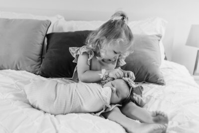 Toddler sister holding newborn baby during in home newborn session