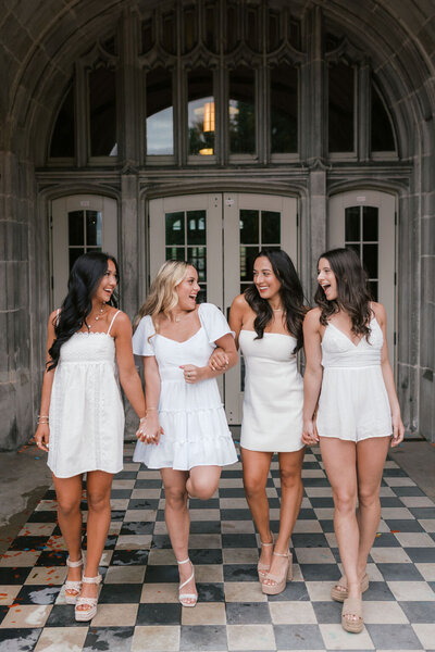 four girls in white dresses hold hands at ayres hall in knoxville tennessee at the university of tennessee