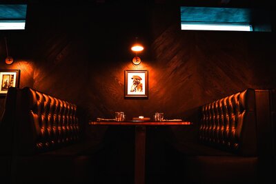 Moody speakeasy booth with tufted leather seating and brass sconce lighting 