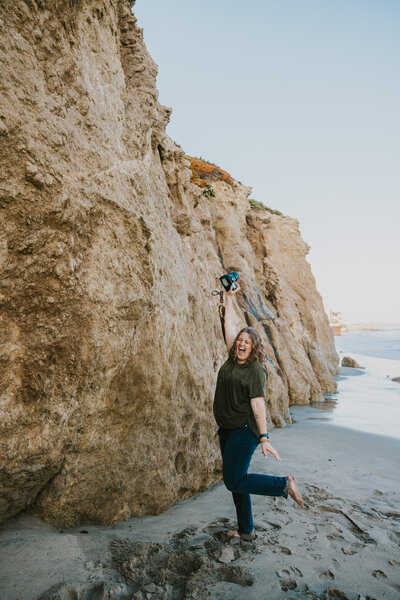 Kayla Marie, Indiana wedding photographer, standing by ocean cliffs, capturing adventurous and authentic love stories.