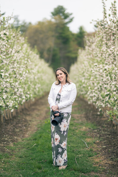 Photographer standing in between rows of apple tress in bloom