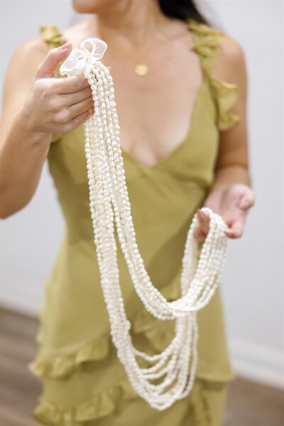 A person holding up a long necklace 