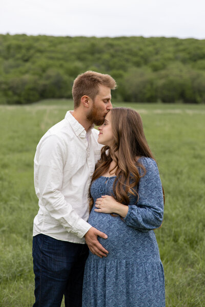 man and woman hugging each other and holding woman's belly for maternity shoot