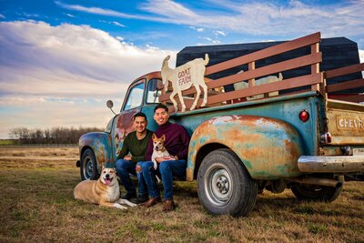 LGBTQ+ couple sit on a 1948 vintage Chevy truck with their dogs at Haute Dog Pet Photography studio.