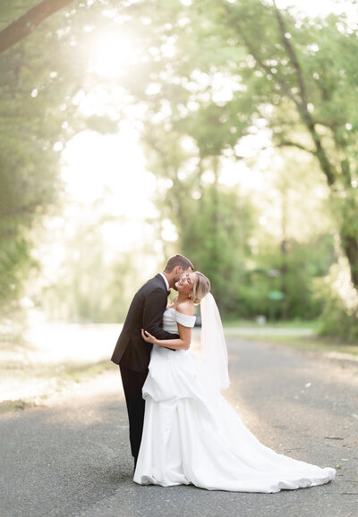 Bride and Groom smiling under the trees in natural light.