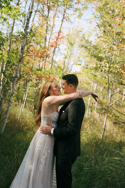A bride and groom holding each other at a wedding in Maine with the ocean behind them.  