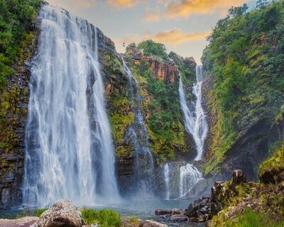 Lush green waterfall with the caption "Reimagined Retreats"