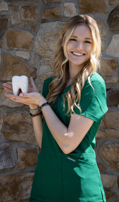 Cassidy Binkley posing for a headshot behind a rustic stone wall. 