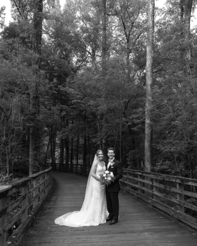 Black and white luxury wedding photo of groom and bride hugging on old wooden bridge in the mountain forests of North Carolina | Megan Smith Photography