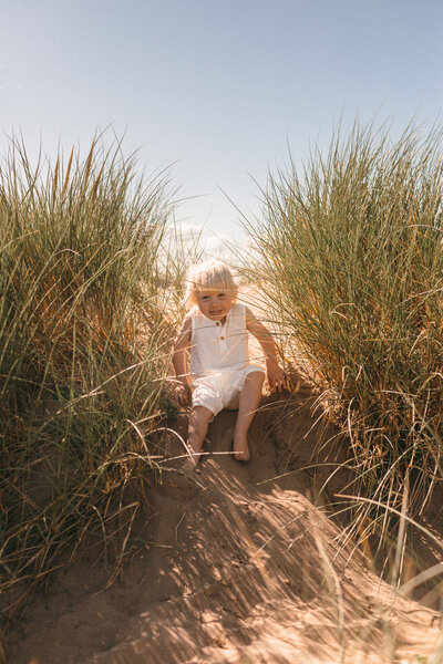 Toddler sliding down sand dunes 
