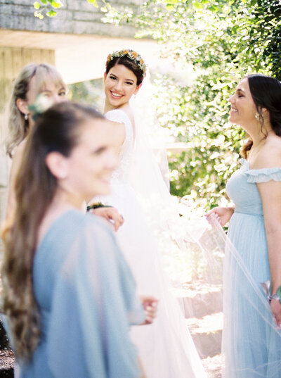 Bride looks over her shoulder and smiles while surrounded by her bridesmaids